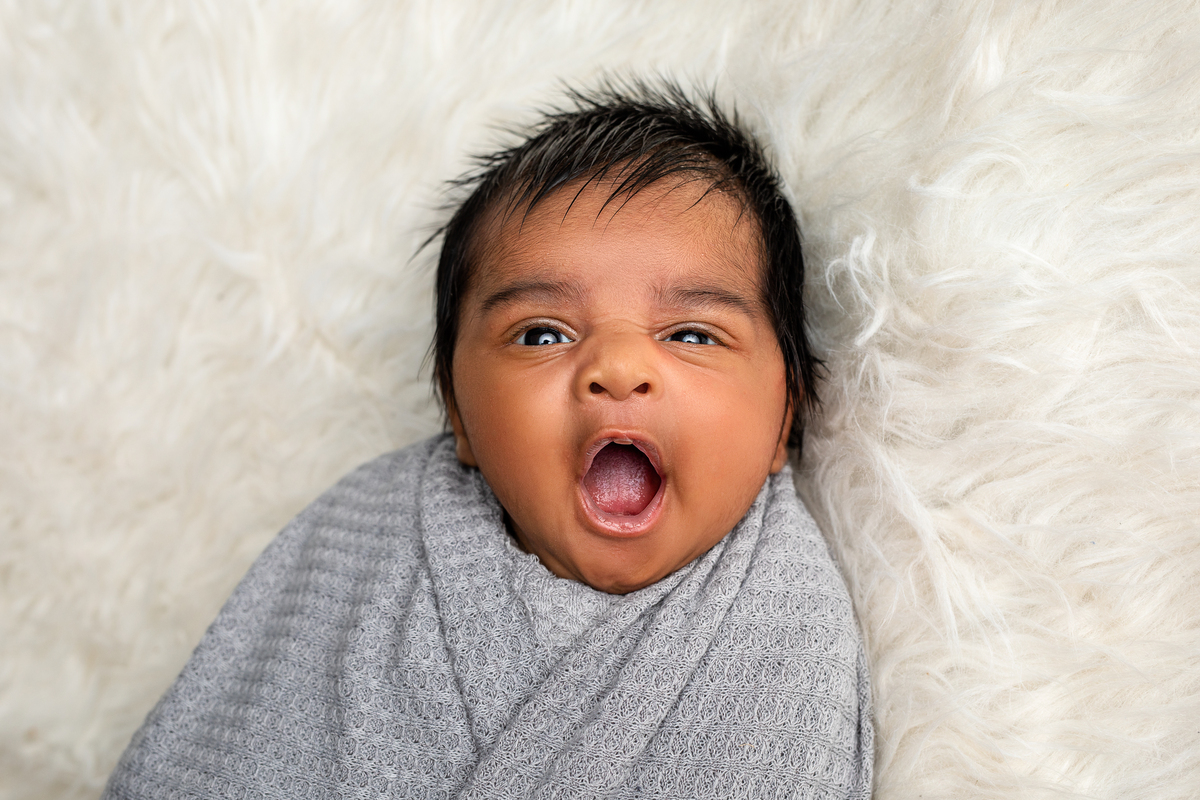 Baby boy laying in a grey swaddle