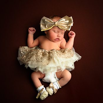 a newborn laying on brown blanket